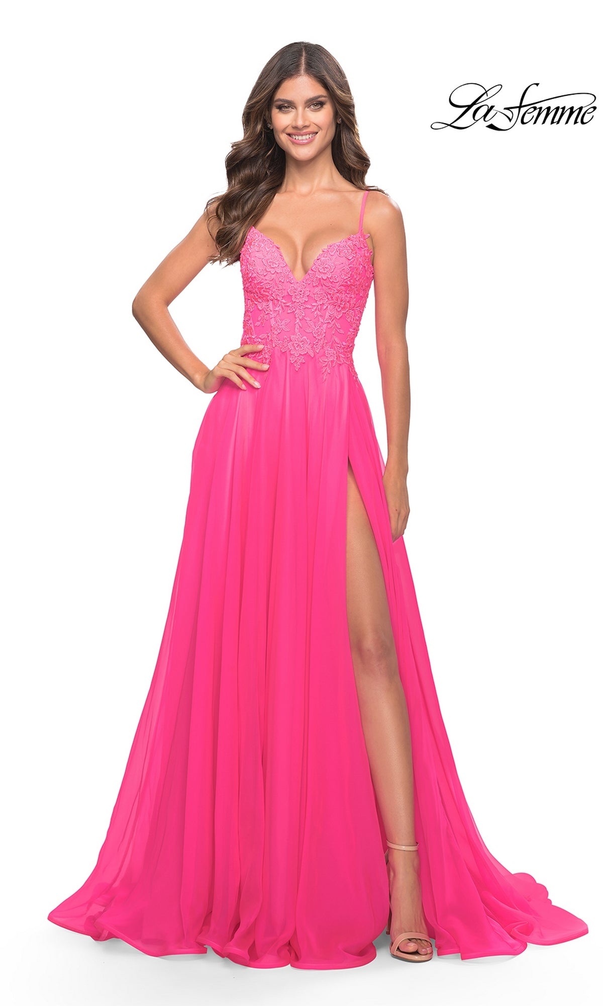 A woman smiles in the La Femme Neon Pink Long A-Line Prom Dress 31506, featuring an embroidered v-neck bodice, spaghetti straps, and a thigh-high slit. The